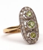 Modern precious metal diamond and peridot ring, the oval shaped pierced panel having three bezel set