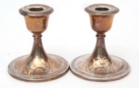 Two George VI squat candlesticks, each with fixed sconces on spreading circular bases (loaded), diam