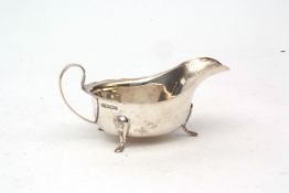 George V sauce boat with cut card rim, strapwork handle on three feet, length 14.8cms, weight approx