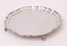 George V silver salver of shaped circular form with polished field and raised on four scrolled feet,