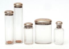 Mixed Lot: five silver lidded and faceted clear glass toiletry bottles, comprising three of