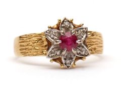 18ct gold ruby and diamond cluster ring, the central circular cut ruby surrounded by six flower