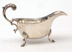 George V sauce boat with cast and applied border, leaf capped handle on three feet, width 14cms,