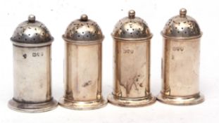 Four Victorian pepper casters each of polished cylindrical form with pierced pull off covers and