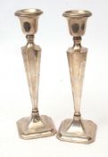Two George V single candlesticks, each with fixed urn shaped sconces on tapering square section
