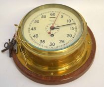 Smith's Astral bulkhead clock in a brass case, mounted on a circular mahogany plinth, 30cms diam