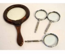 Mahogany circular hand held magnifying glass together with three smaller steel framed magnifying