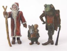 Three various cold painted figures including St Nicholas, together with a toad smoking a cigarette