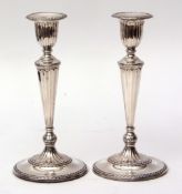 Two George V single candlesticks, each with detachable sconces to urn shaped nozzles on tapering and