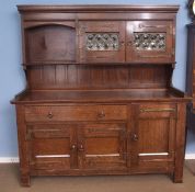 A Liberty & Co oak dresser, (marked with ivorine plaque inside drawer), the pediment with two leaded