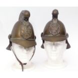 Two early 20th century French brass firemen's helmets, each with scrolling crest and riveted badge