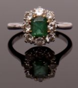 Emerald and diamond cluster ring featuring a rectangular step cut emerald, claw set and raised
