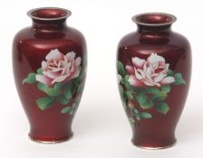 Pair of Japanese cloisonne and gin bari enamel vases with sprays of roses against a translucent ruby