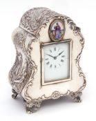 Late Victorian silver cased mantel timepiece, the shaped and waisted case with cast panels depicting