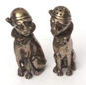 Pair of novelty pepper casters, each modelled in the form of a seated Mastiff, each wearing a cap