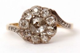 Precious metal and diamond cluster ring, the diamond set flower head supported by cross-over
