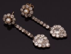 Pair of diamond and pearl pendant earrings, each surmount a pearl in a diamond surround suspending