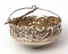 Early 20th century American tea strainer of basket form with C-scroll and foliate embossed border,