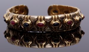 Yellow metal sapphire and ruby set bangle, the stylised design, alternate set with cabochon rubies