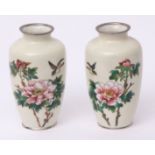 Pair of Japanese cloisonne vases with birds flying above sprays of peony against an ivory coloured