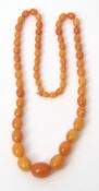 An amber-type necklace, a single row of graduated beads, 22mm to 8mm, of egg yolk and butterscotch