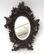 Black Forest oval wall mirror, the carved frame decorated with exotic birds and foliage, circa early