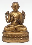 Rare fine and delicately cast Sino Tibetan gilt bronze of a Lama seated cross-legged on a lotus base