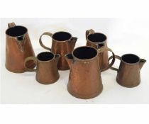 Two sets of graduated GWR stamped copper jugs, graduating from quart to pint to half pint (6)