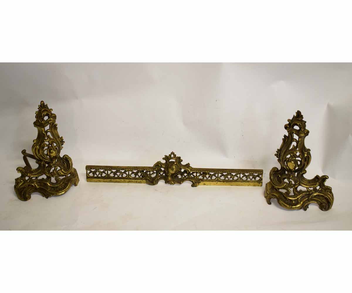 Pair of brass rococo pierced fire dogs together with central fender section with pierced front,