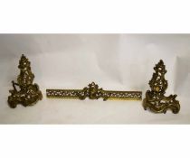 Pair of brass rococo pierced fire dogs together with central fender section with pierced front,