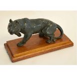 Green ground spelter type figure of a tiger on a wooden base, 26cms long