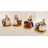 Group of four 19th century Continental figures of seated ladies with blue and gilded overcoats, to