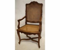 Stained beech carver chair with cane back and seat, arms and back carved with geometric foliage etc