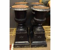 Set of four Victorian style black painted cast metal urns of campana form on stands, 114cms high