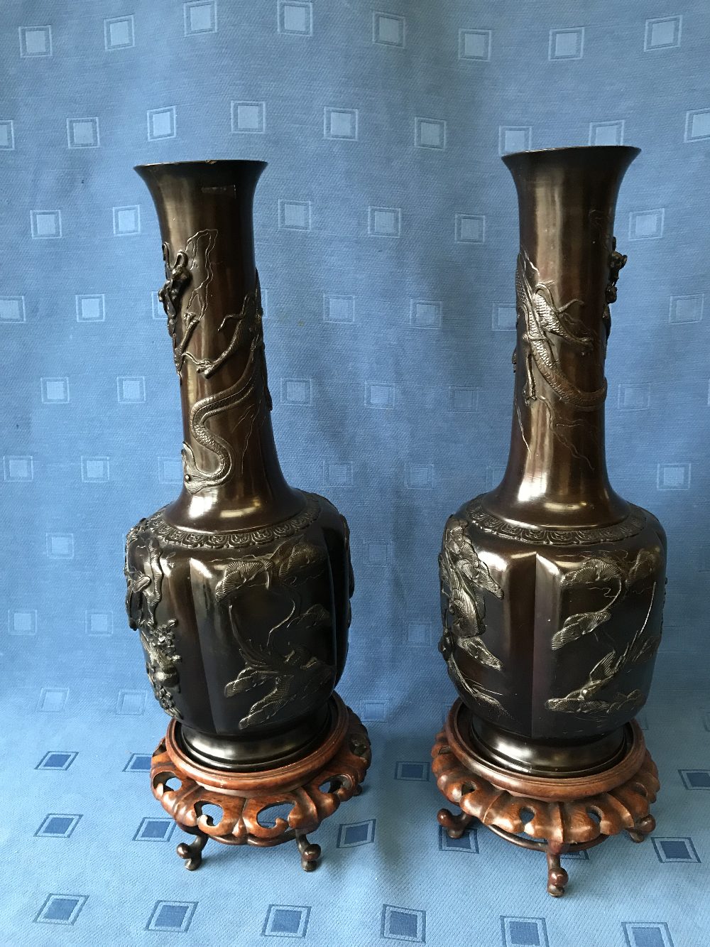 Pair of Chinese bronze onion shaped vases with raised decoration of birds & dragons on carved wooden