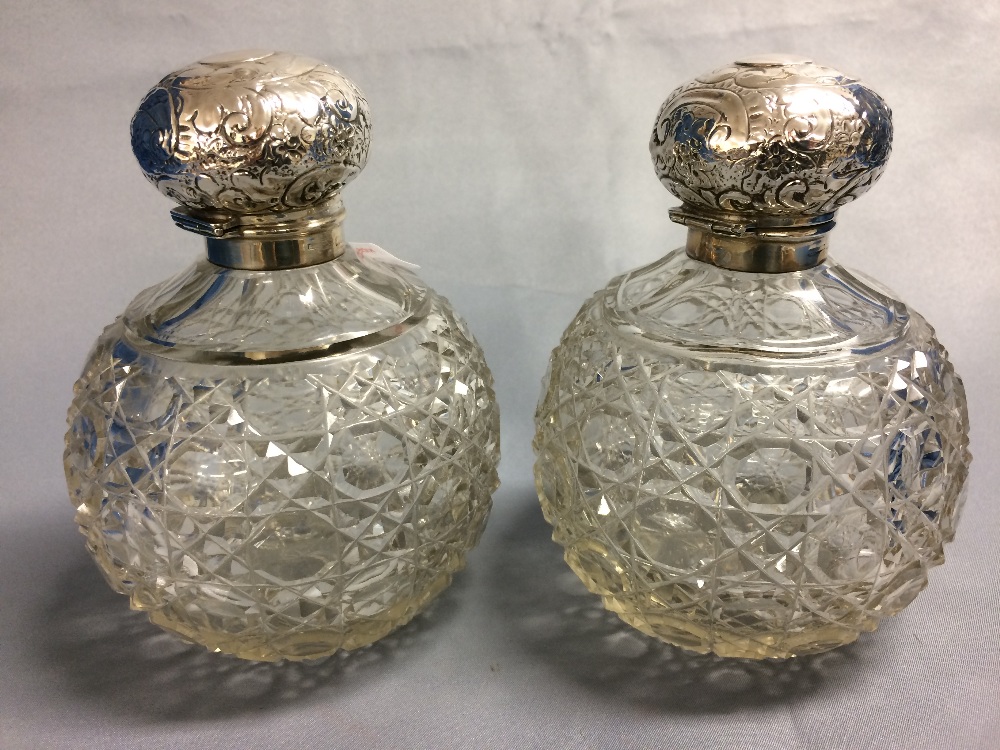 Pair of spherical glass cologne bottles with embossed hallmarked silver hinged lids, Birmingham