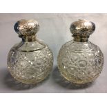 Pair of spherical glass cologne bottles with embossed hallmarked silver hinged lids, Birmingham