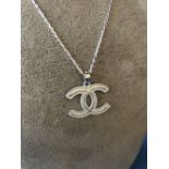 Silver pendant necklace in the shape of two interlocking C's on silver chain