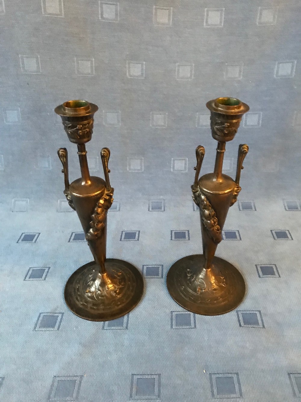 Pair of C19th elegant bronze slender circular candlesticks decorated with swags of flowers & mask