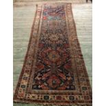Antique Caucasian runner with central panel of motifs in strong colours on dark navy blue ground and