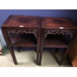 Pair of Chinese hardwood two tier stands with pierced carved frieze on block legs, 79cmH