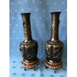 Pair of Chinese bronze onion shaped vases with raised decoration of birds & dragons on carved wooden