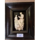 C19th carved ivory plaque of robed mother & child supported on a winged head in a mahogany frame,