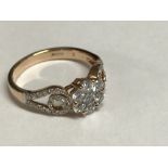 18 carat rose gold diamond ring, the central stone flanked by two scrolling diamond set shoulders