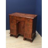 C18th style walnut veneered kneehole desk with 7 drawers around a central cupboard on bun feet,