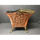 Burnished embossed copper coal scuttle with brass swing handle on 4 paw feet