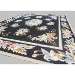 A large hand woven Needlepoint carpet with large blue, pink and cream floral motifs on black