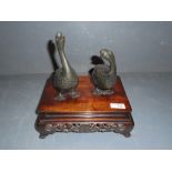 Pair of Japanese Meiji period bronze geese, each raised on a hardwood base, geese 18cm (largest)