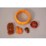 Four Chinese amber carvings and a bangle.