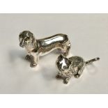 Two silver animal figures to include a dachshund and a cat with emerald eyes